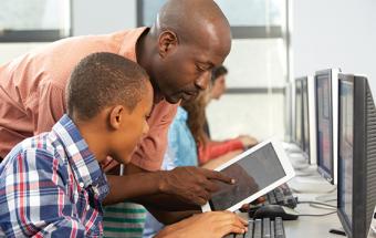 African American male educator with tablet working with young male African American student