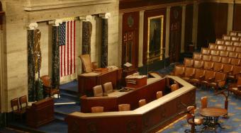 The chamber of the house of representatives with a large American flag displayed.